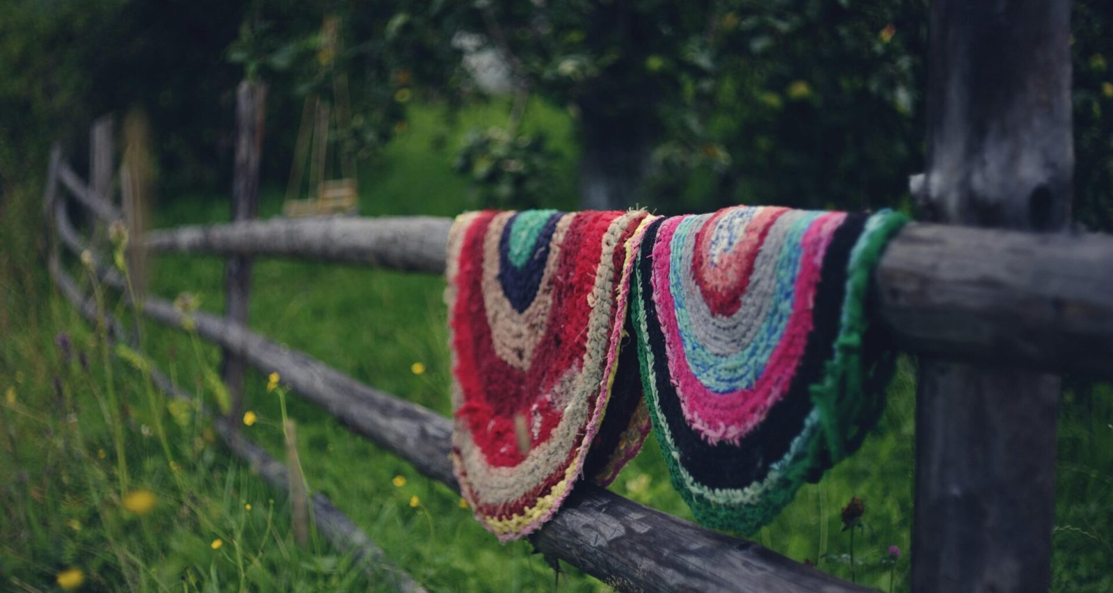 Decke hängt an einem Holzzaun in einem Feld mit grasbewachsener Umgebung im Freien