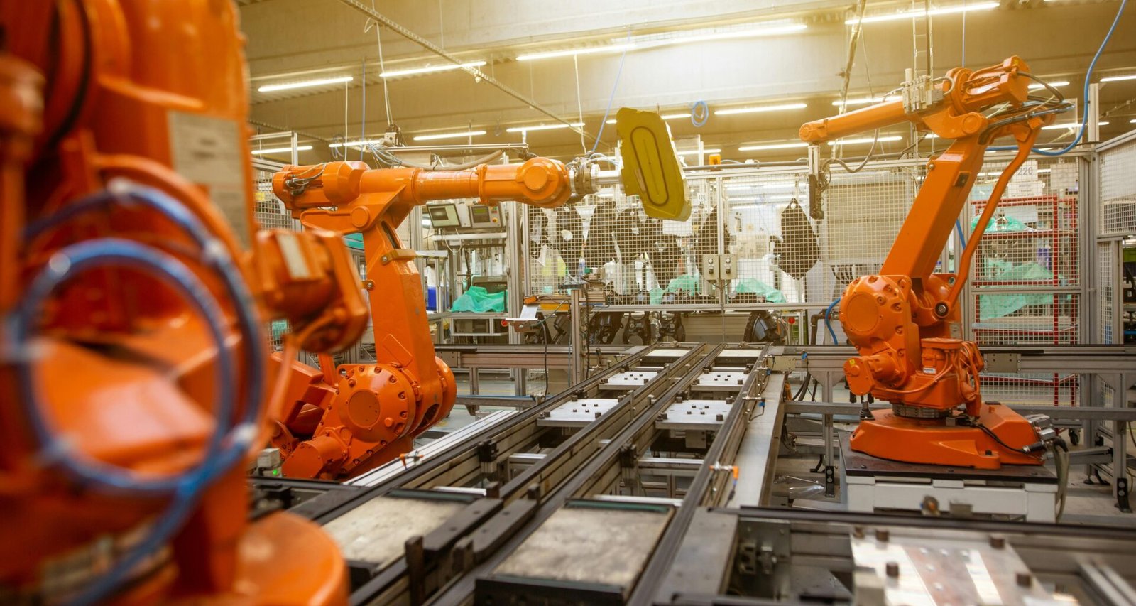 Innenansicht einer Fabrik mit vielen orangefarbenen Maschinen, die für automatisierte Fertigung angeordnet sind.