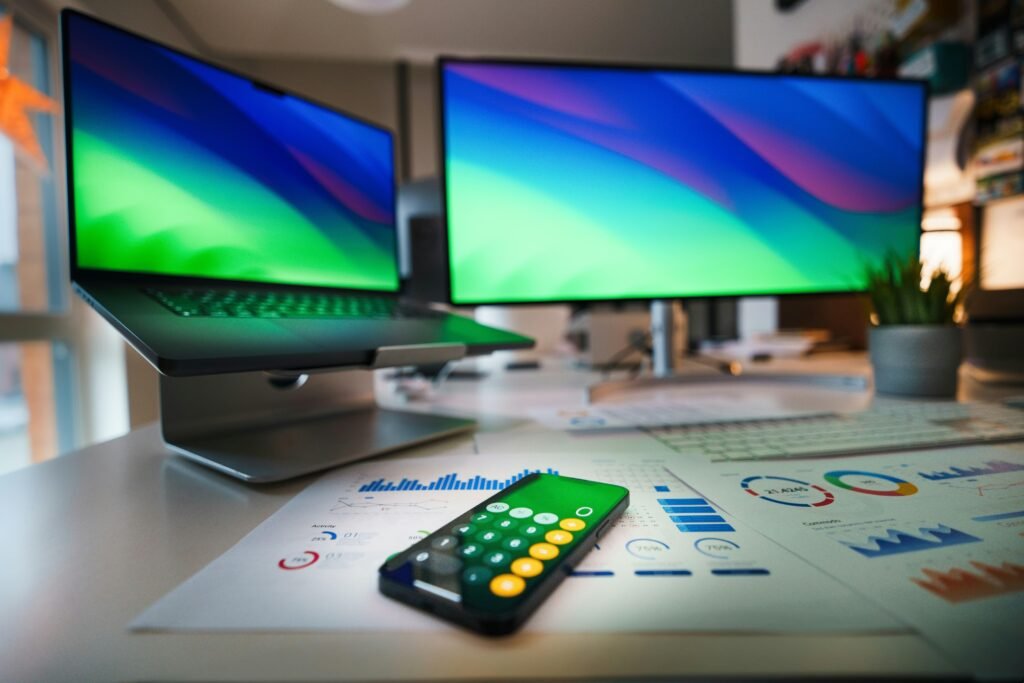 Eine Fernbedienung liegt auf einem Schreibtisch neben zwei Computer-Monitoren und verdeutlicht einen modernen Arbeitsplatz.