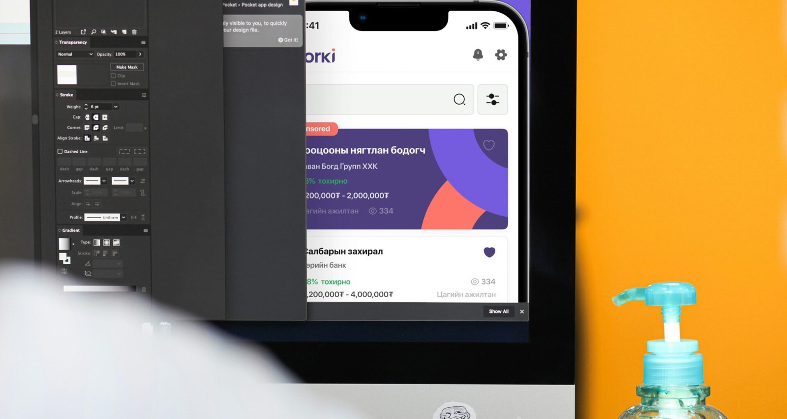 Eine Flasche Handdesinfektionsmittel steht neben einem Computerbildschirm auf einem Arbeitsplatz.