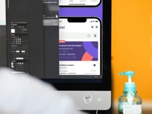 Eine geöffnete Flasche Handdesinfektionsmittel steht neben einem Computerbildschirm auf einem Arbeitstisch.