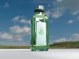 Mineralwasserflasche vor einem bewölkten Himmel, dargestellt als Symbol für Frische und Reinheit