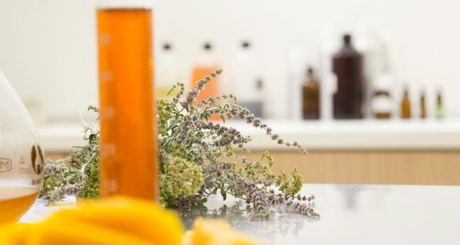 Eine durchsichtige Flasche mit orangefarbener Flüssigkeit steht auf einem Tisch in natürlichem Licht