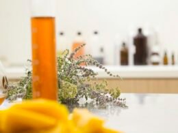 Eine durchsichtige Flasche mit orangefarbener Flüssigkeit steht auf einem Tisch in natürlichem Licht