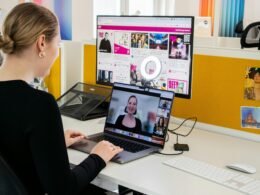 Eine Frau sitzt an einem Schreibtisch und arbeitet konzentriert an einem Laptop in einem hellen Büro.