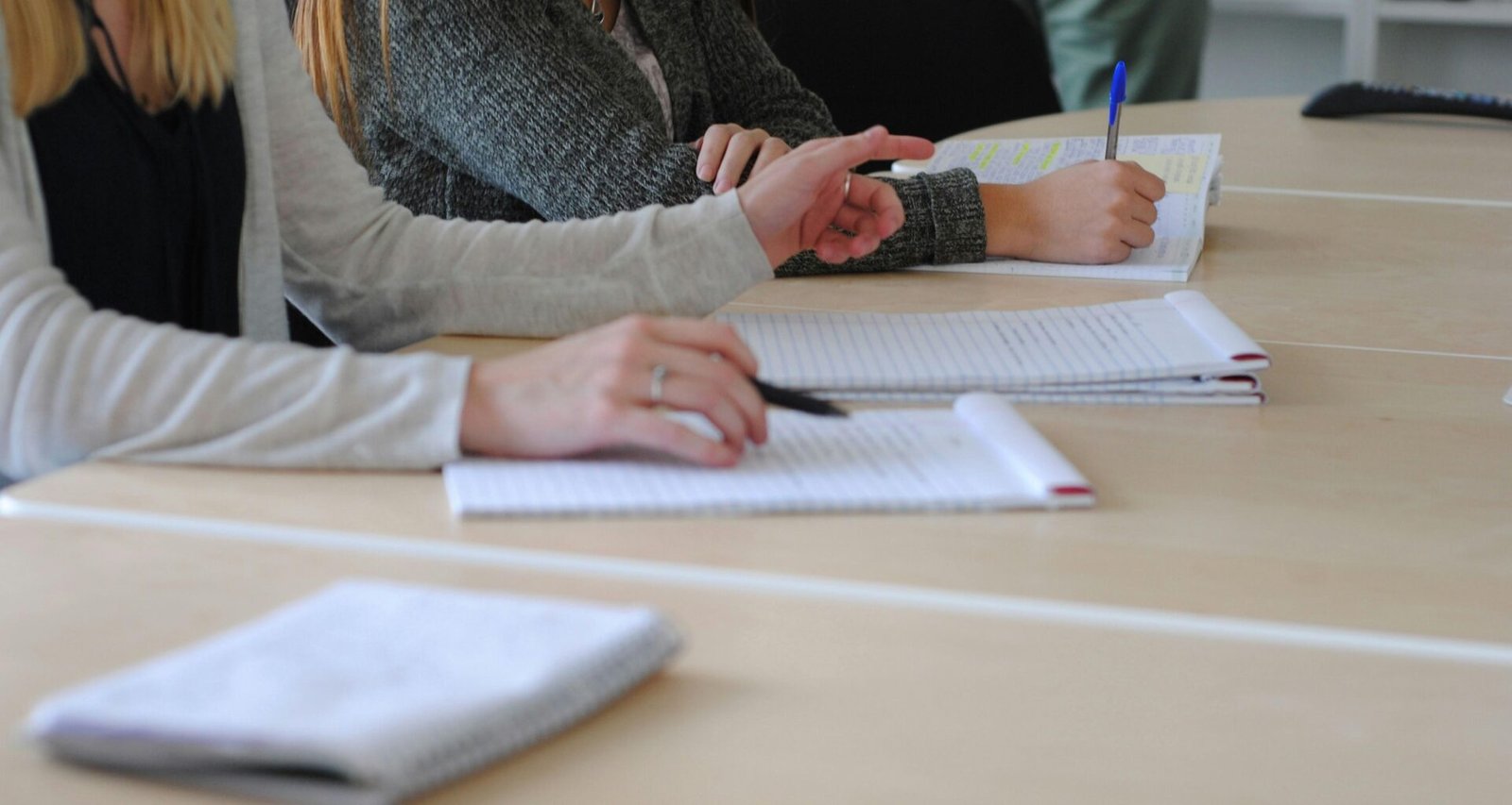 Frau sitzt am Tisch und schreibt auf einem Blatt Papier, um Aufgaben zu organisieren oder Notizen zu machen.
