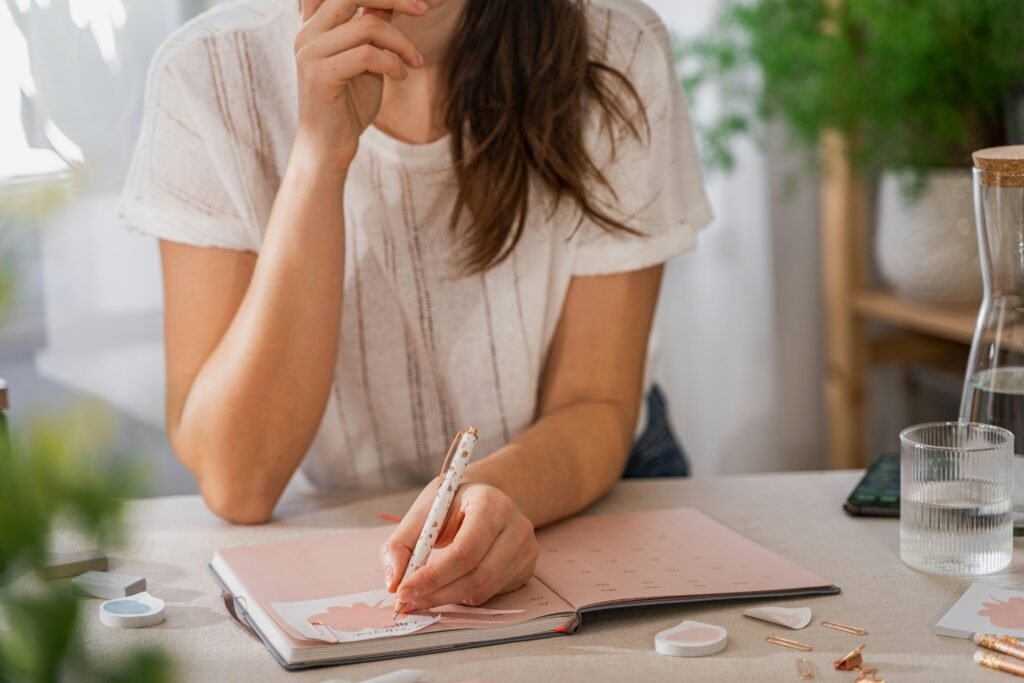 Eine Frau schreibt handschriftlich auf ein Blatt Papier an einem Tisch in einem hellen Raum