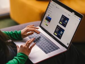 Eine Frau sitzt auf einem Sofa und arbeitet an einem Laptop, ideal für Themen zu Homeoffice oder digitalem Arbeiten.