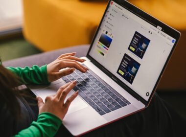 Eine Frau sitzt auf einem Sofa und arbeitet an einem Laptop – modernes Arbeiten von zu Hause aus, entspannt im Wohnbereich.