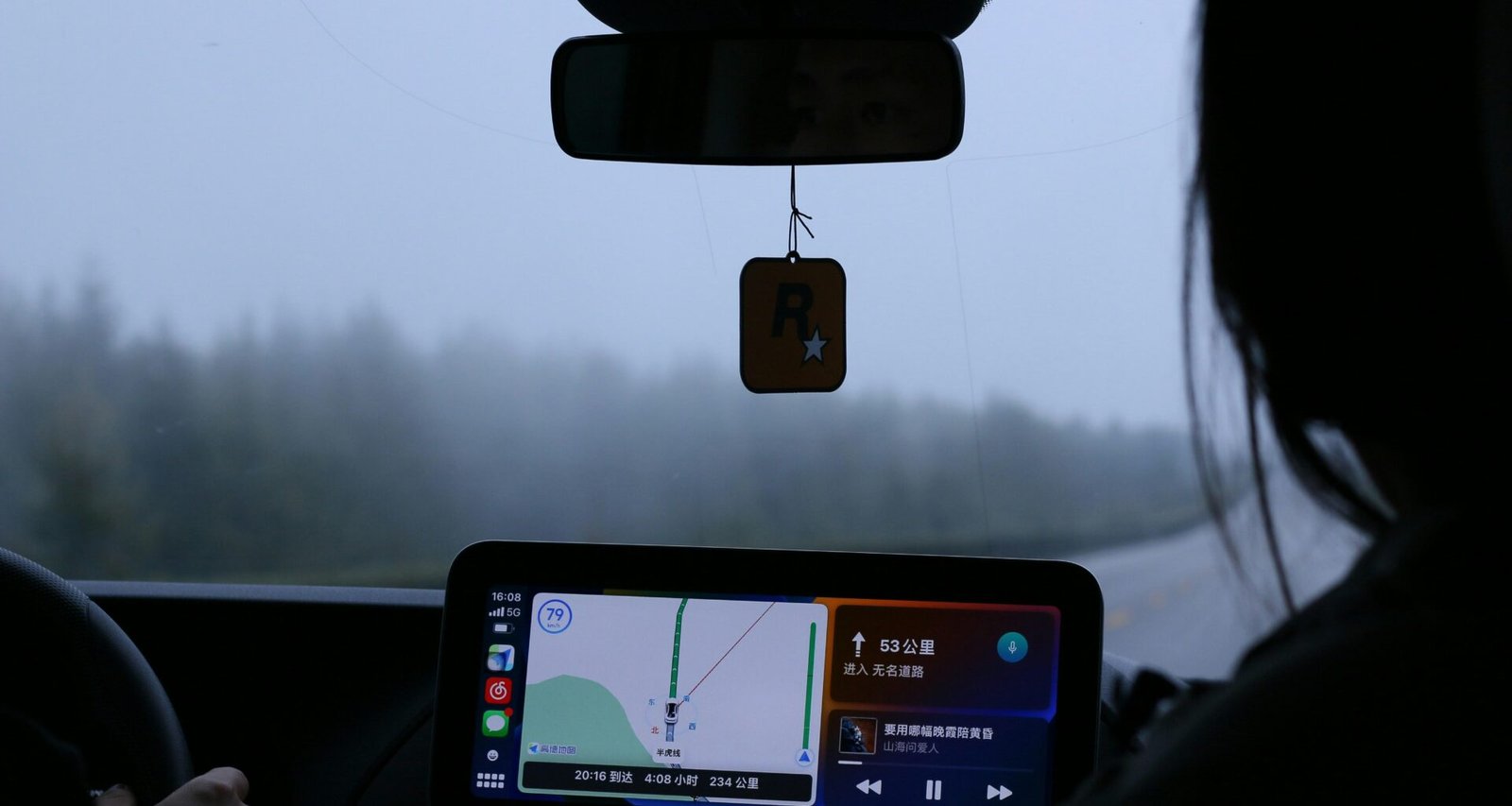 Eine Frau sitzt am Steuer eines Autos und hält ein Mobiltelefon während der Fahrt in der Hand.