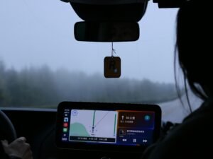 Eine Frau sitzt am Steuer eines Autos und hält ein Mobiltelefon während der Fahrt in der Hand.