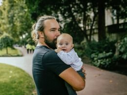 Eine Frau steht und hält ein Baby im Arm. Das Baby blickt zur Frau, beide sind im Innenraum zu sehen.