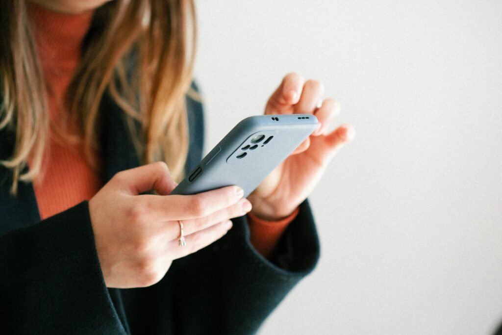Eine Frau hält ein Smartphone in den Händen, Bild zeigt Fokus auf mobile Technik und moderne Kommunikation.