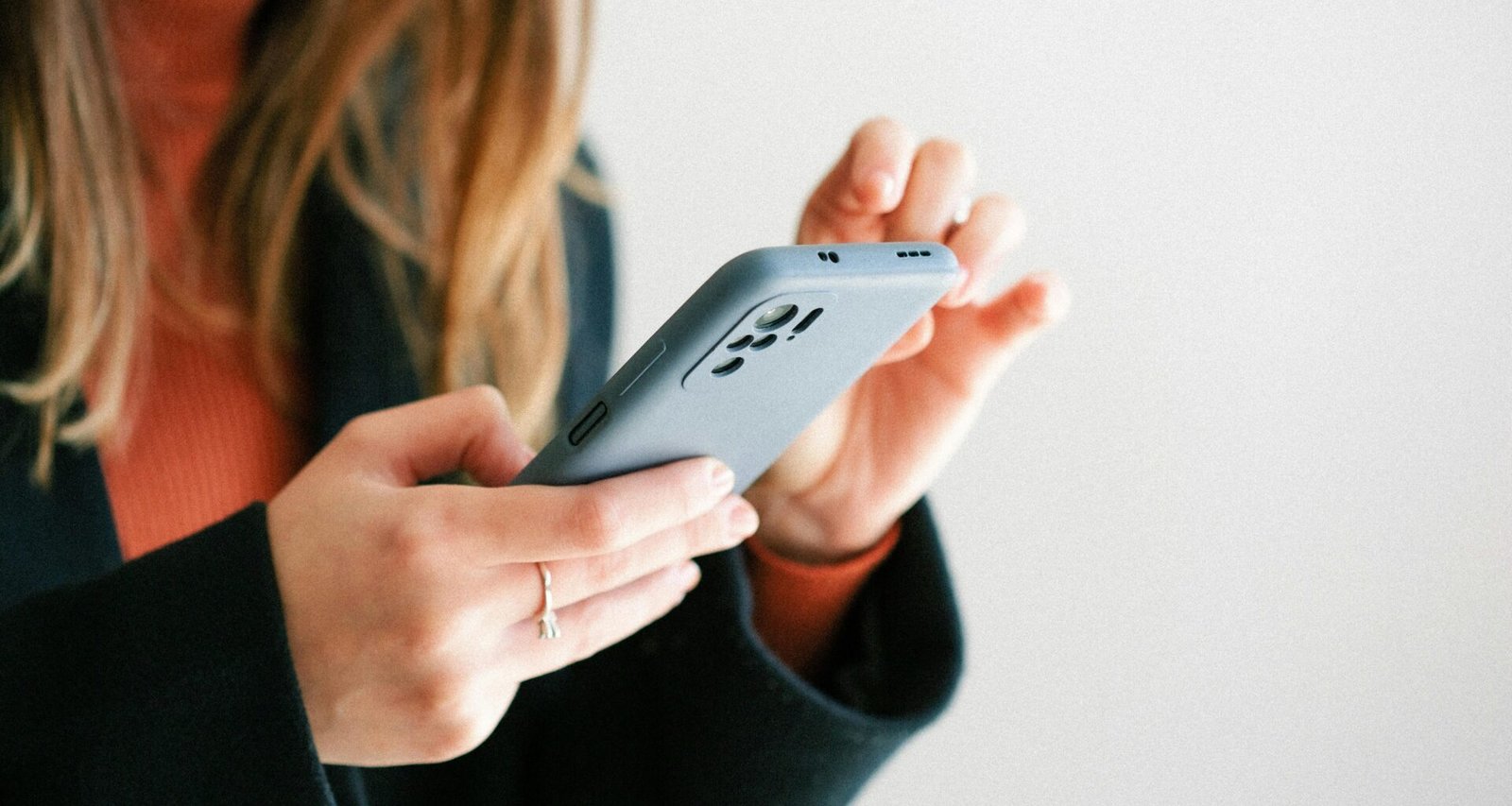 Eine Frau hält ein Smartphone in den Händen, Bild zeigt Fokus auf mobile Technik und moderne Kommunikation.
