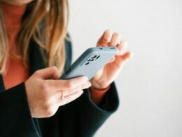 Eine Frau hält ein Smartphone in den Händen, Bild zeigt Fokus auf mobile Technik und moderne Kommunikation.