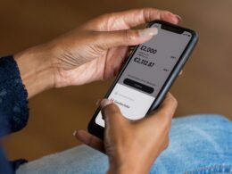 Frau hält ein Smartphone in der Hand und blickt auf das Display, moderne Techniknutzung im Alltag