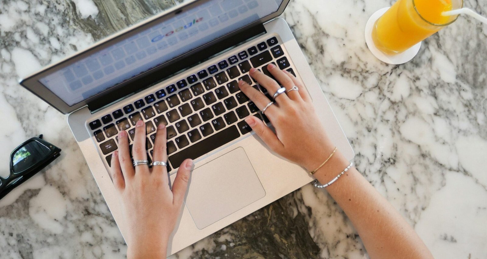 Eine Frau sitzt an einem Marmortisch und arbeitet konzentriert an ihrem Laptop, dezente Raumgestaltung im Hintergrund.