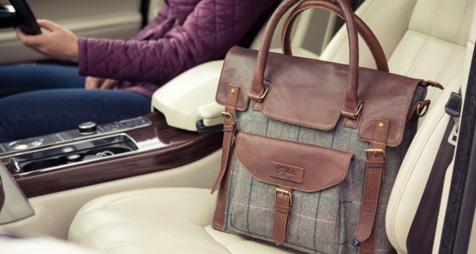 Eine Frau sitzt auf dem Fahrersitz eines Autos und hält ein Smartphone in der Hand, modernes Kommunikationsmittel im Einsatz.