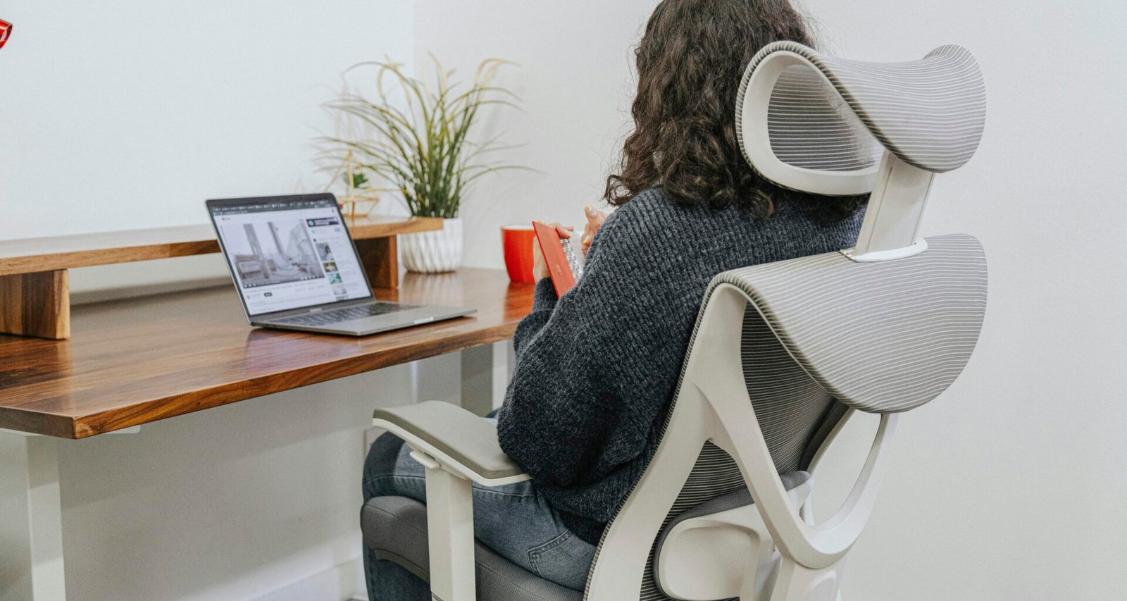 Frau sitzt an einem Schreibtisch und arbeitet an einem Laptop in einem modernen Büro