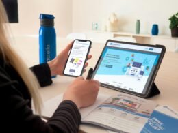 Eine Frau sitzt an einem Tisch in einem modernen Raum und verwendet ein Tablet zur digitalen Arbeit oder Recherche.