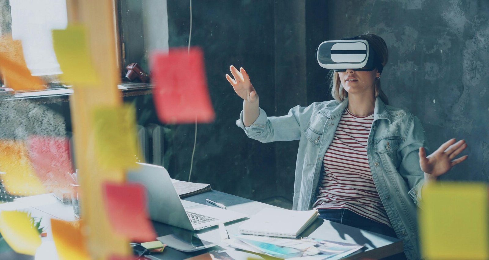 Junge Frau erforscht mit ausgestreckten Händen eine virtuelle Realität und trägt eine VR-Brille