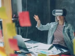 Junge Frau erforscht mit ausgestreckten Händen eine virtuelle Realität und trägt eine VR-Brille