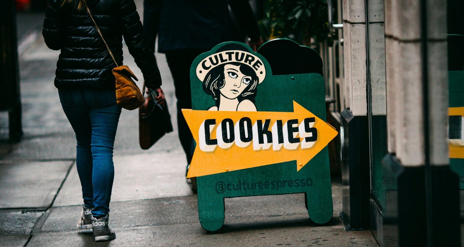 Eine Frau läuft auf dem Bürgersteig an einem großen Schild vorbei, das für Cookies wirbt.