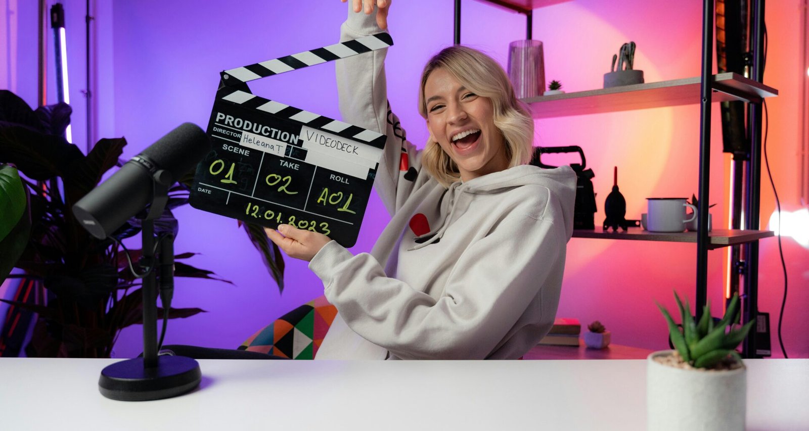 Eine Frau steht vor einer Kamera und hält eine Filmklappe vor sich, bereit für den Drehbeginn