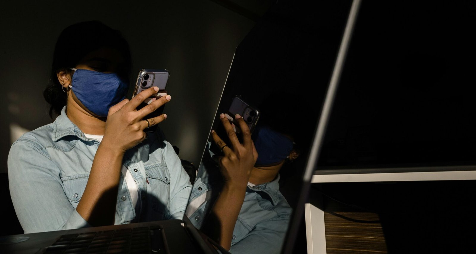 Eine Frau mit blauem Hemd hält ein Smartphone und schaut auf das Display, moderne digitale Kommunikation.