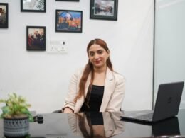 Eine Frau sitzt an einem Schreibtisch und arbeitet an einem Laptop, Büroalltag und moderne Technik im Fokus.