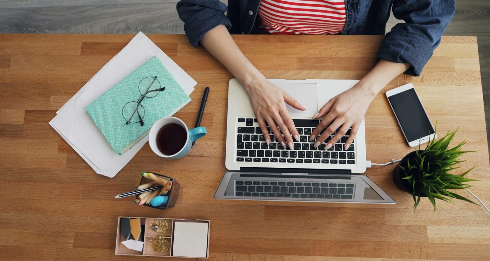 Frau sitzt an einem Tisch und arbeitet an einem Laptop, konzentriert im modernen Homeoffice-Umfeld