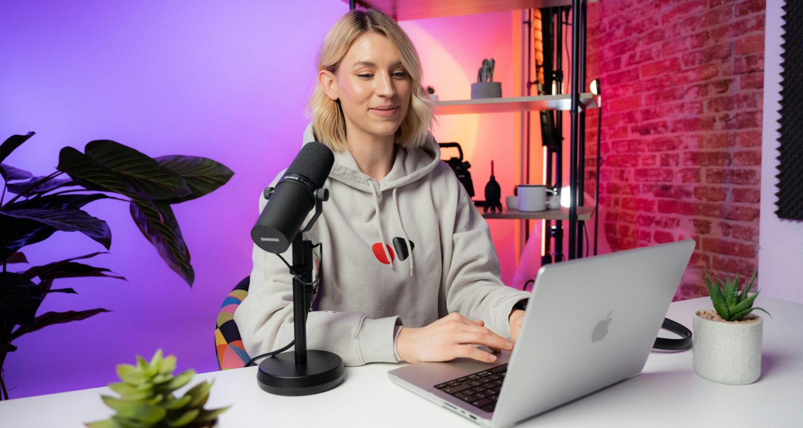 Eine Frau sitzt an einem Schreibtisch und arbeitet an einem Laptop, moderne Arbeitsumgebung, Fokus auf Remote-Arbeit.