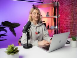 Eine Frau sitzt vor einem Laptop an einem Schreibtisch, typische Szene im Homeoffice oder modernen Büroalltag.