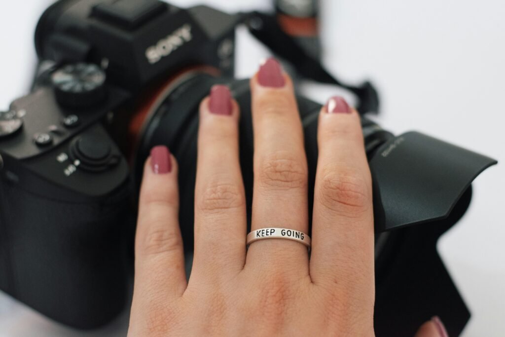 Nahaufnahme einer Frauenhand mit Ring, die eine Kamera am Handgelenk hält, ideal für Technik- und Lifestyle-Themen.