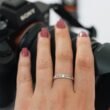 Nahaufnahme einer Frauenhand mit Ring, die eine Kamera am Handgelenk hält, ideal für Technik- und Lifestyle-Themen.