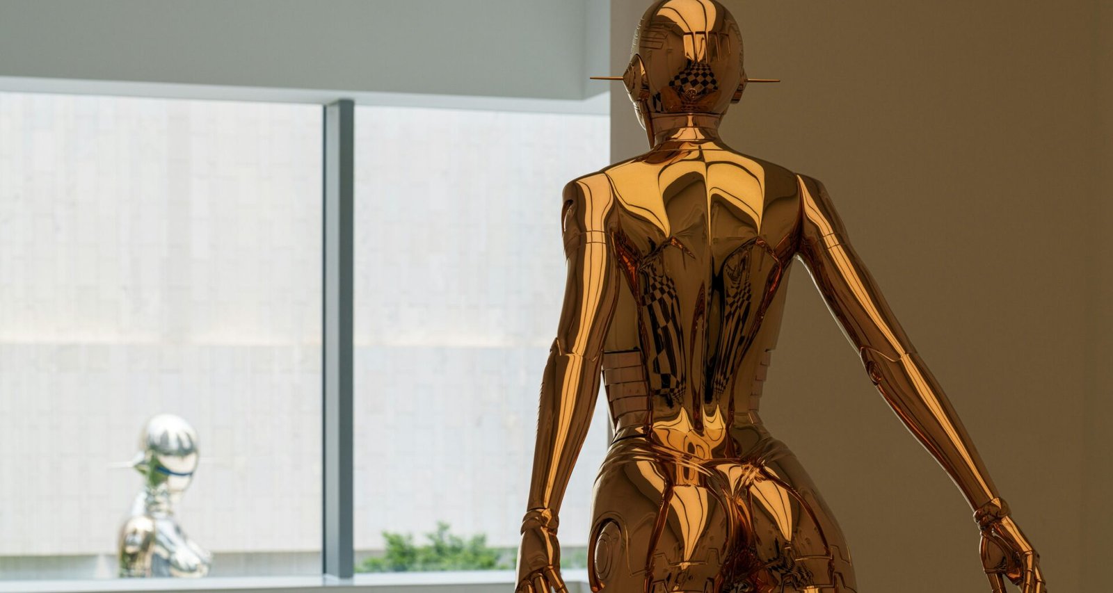 Goldene Statue steht nahe an einem Fenster, das Tageslicht fällt darauf und unterstreicht Details der Figur