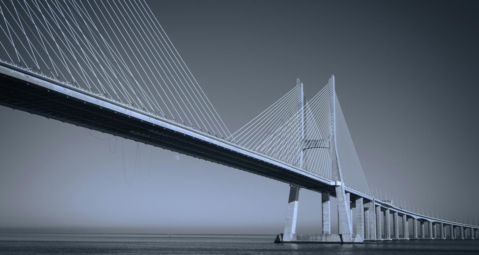 Große Brücke aus Stahl und Beton überspannt ein weitläufiges Gewässer bei Tageslicht