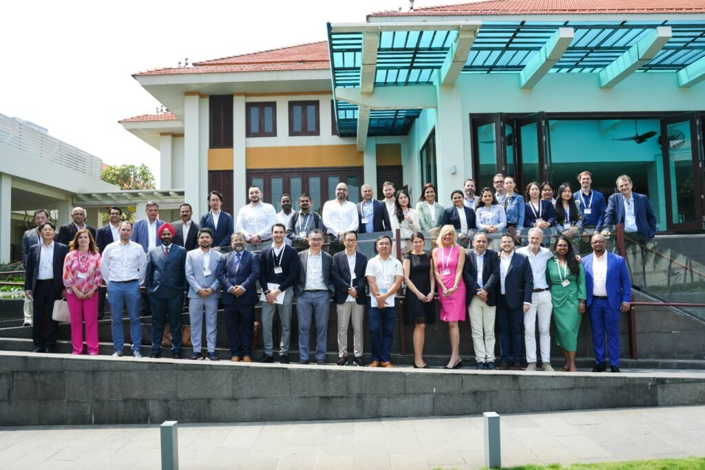 Große Menschengruppe steht gesammelt im Außenbereich vor einem modernen Gebäudeeingang, Tageslicht, urbanes Umfeld