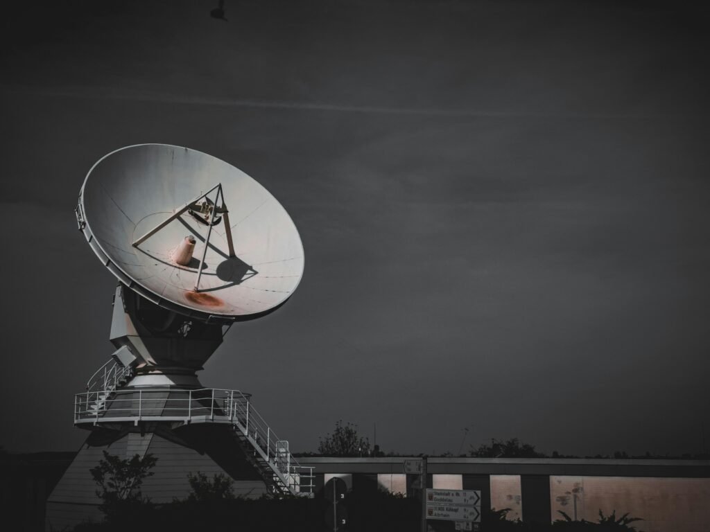 Große Satellitenschüssel auf einer erhöhten Metallplattform für Kommunikations- und Signalübertragung im Freien