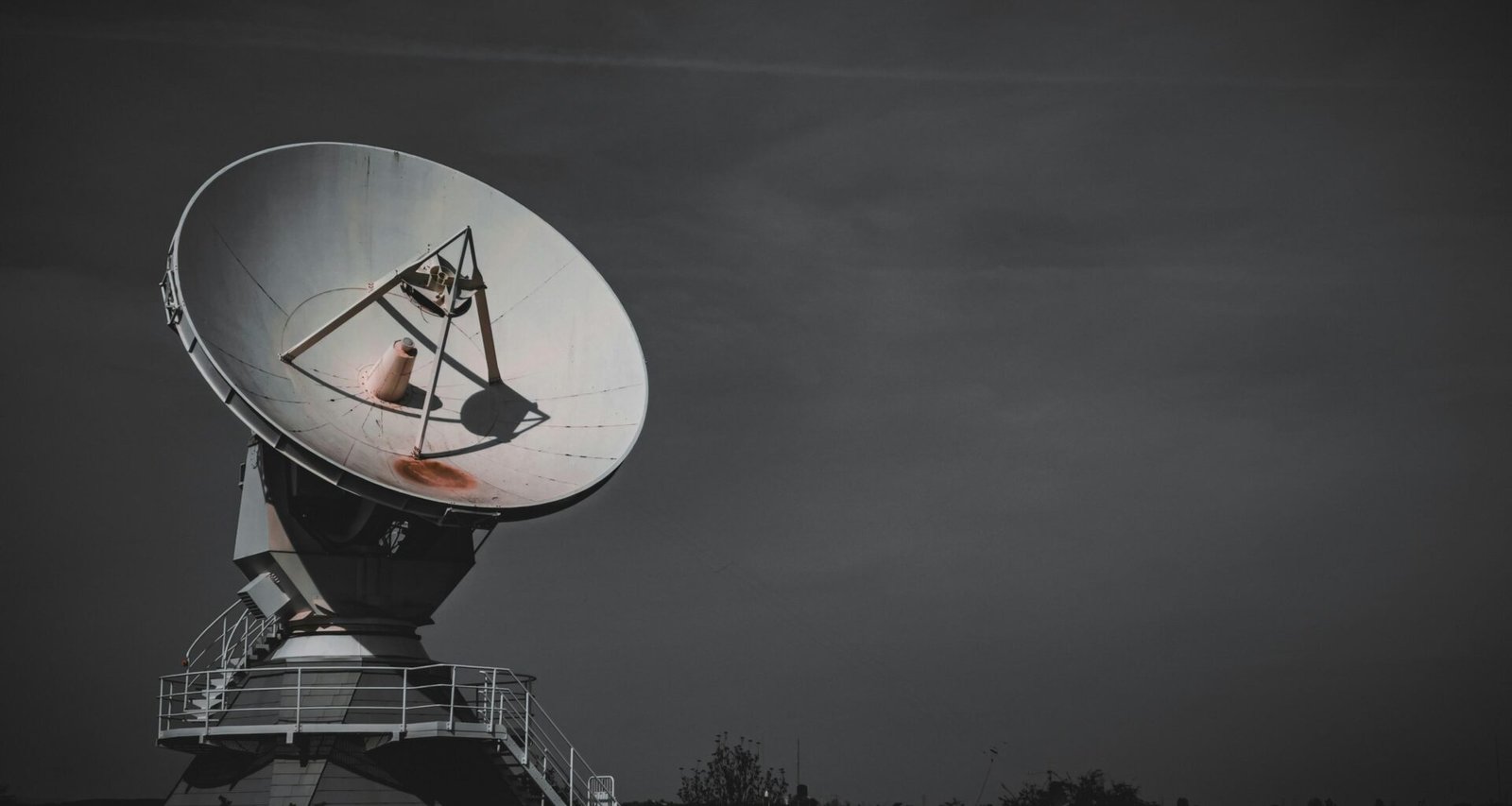 Große Satellitenschüssel auf einer erhöhten Metallplattform für Kommunikations- und Signalübertragung im Freien