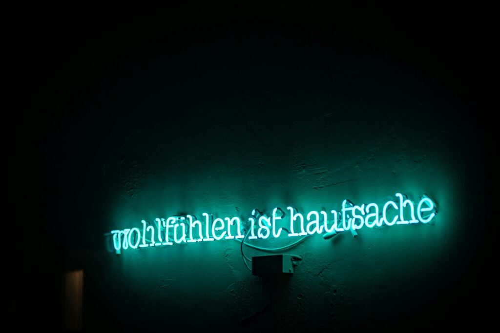 Grünes Neon-Schild mit der Aufschrift 'wultuhten ist hausnace' an einer Wand, fotografiert von Maximalfocus.