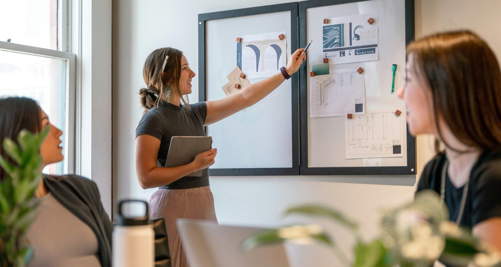 Mehrere Frauen sitzen gemeinsam an einem Tisch und arbeiten an einem Projekt in modernem Büroambiente.