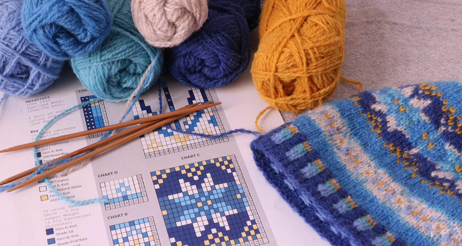 Mehrere bunte Wollknäuel befinden sich nebeneinander auf einer ebenen Tischfläche.