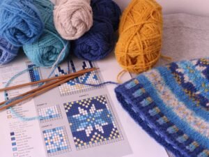 Mehrere bunte Wollknäuel befinden sich nebeneinander auf einer ebenen Tischfläche.