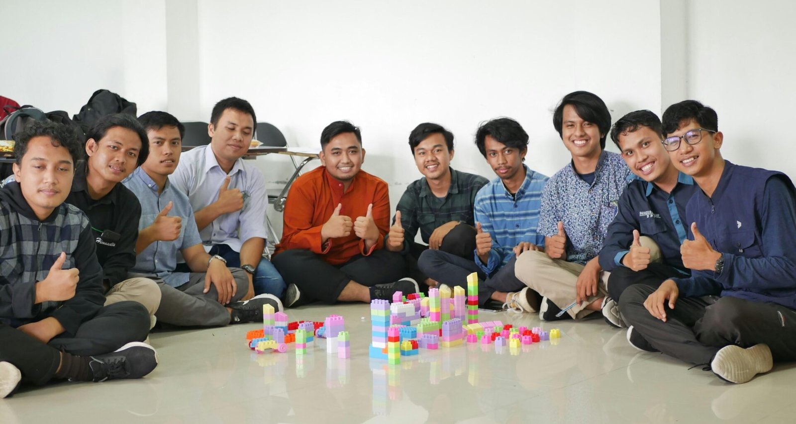 Mehrere Männer sitzen nebeneinander und unterhalten sich in einem modernen, lichtdurchfluteten Raum.