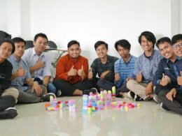 Mehrere Männer sitzen nebeneinander und unterhalten sich in einem modernen, lichtdurchfluteten Raum.