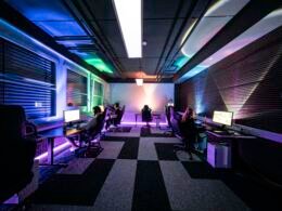 Mehrere Personen sitzen in einem hellen Raum an Schreibtischen und arbeiten gemeinsam am Computer.