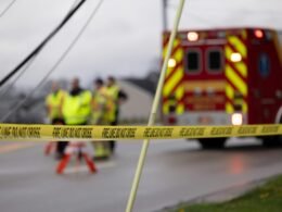 Eine Gruppe von Menschen steht in Arbeitskleidung neben einem roten Feuerwehrwagen im Freien.