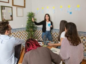 Mehrere Personen sitzen um einen Holztisch und diskutieren gemeinsam über aktuelle Arbeitsinhalte in einem Büro.