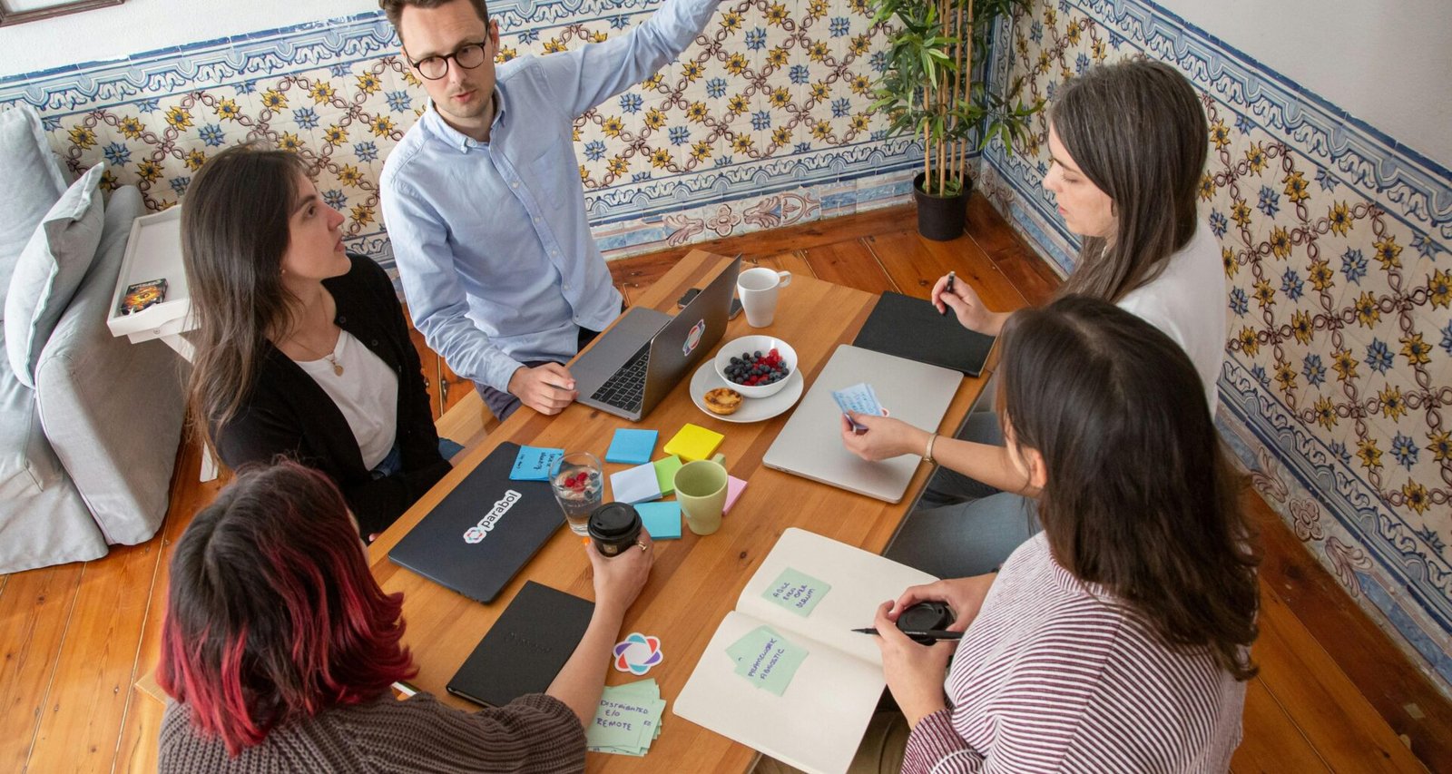 Mehrere Personen sitzen bei einem Teammeeting um einen großen Holztisch und arbeiten gemeinsam an Ideen.